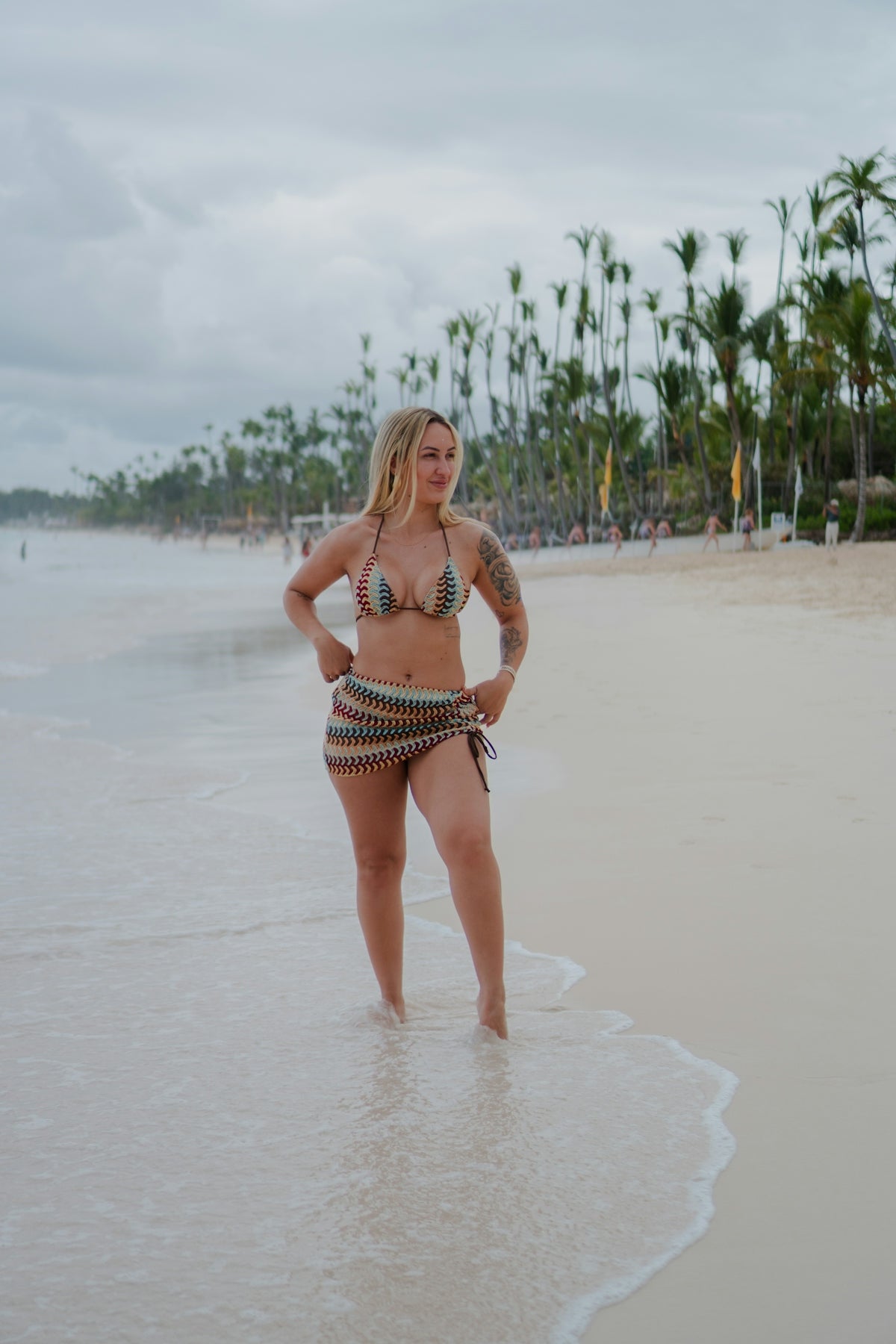 Woman in bikini standing on a sandy beach.