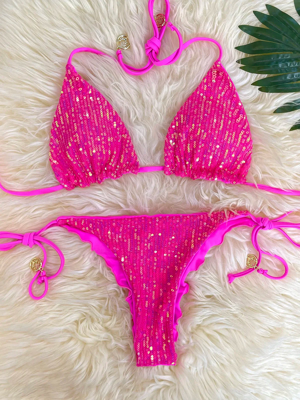 Hot pink sequin triangle bikini set with ruffle thong bottom on white fur with palm leaf
