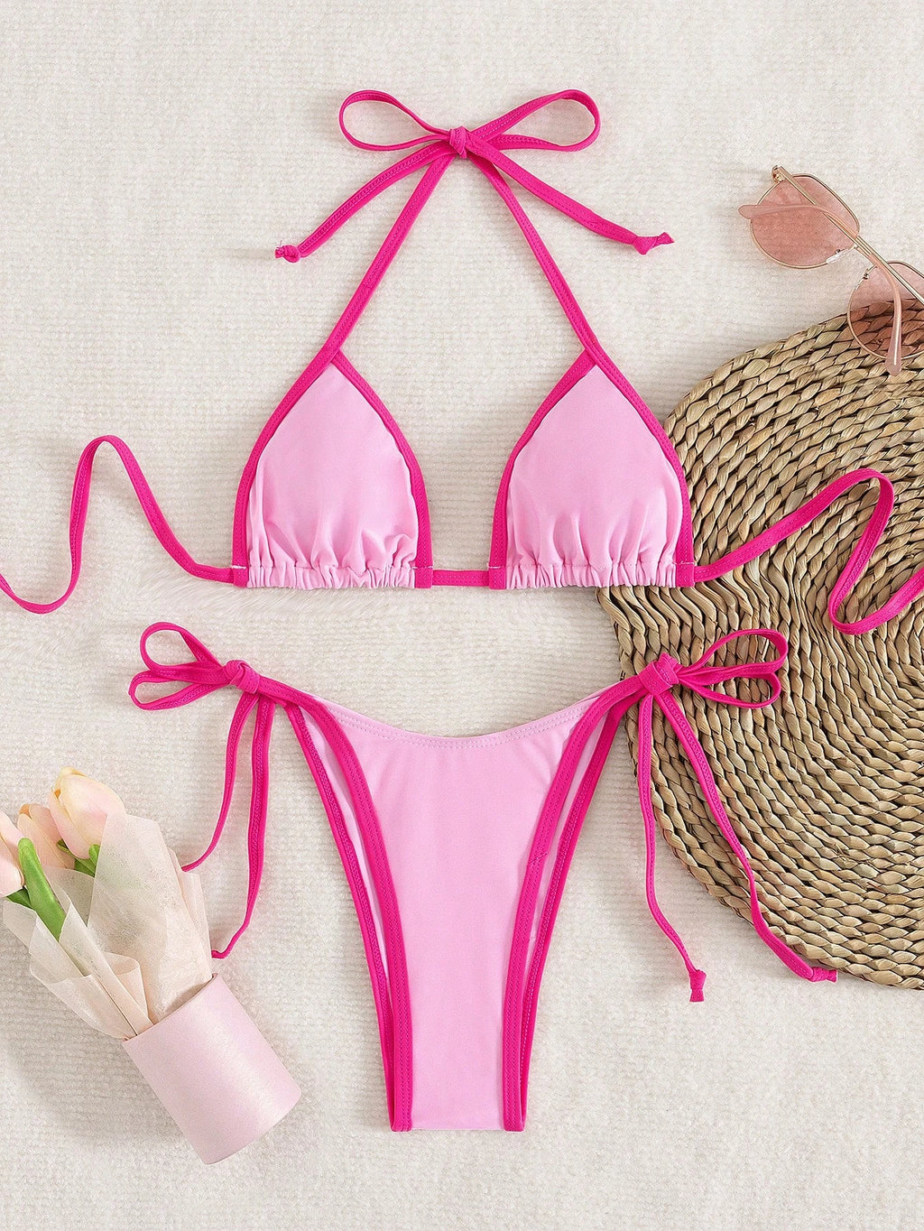 pink triangle halter bikini top with fuchsia contrast trim laid flat with matching pink micro thong bottom