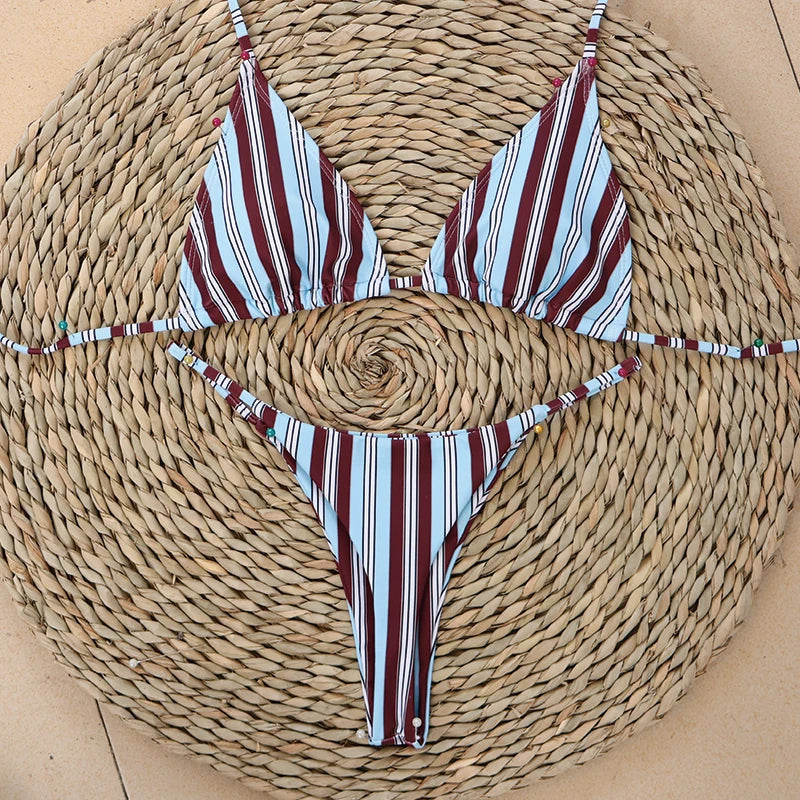Burgundy stripe triangle bikini top and matching bottoms shown flat on a straw mat