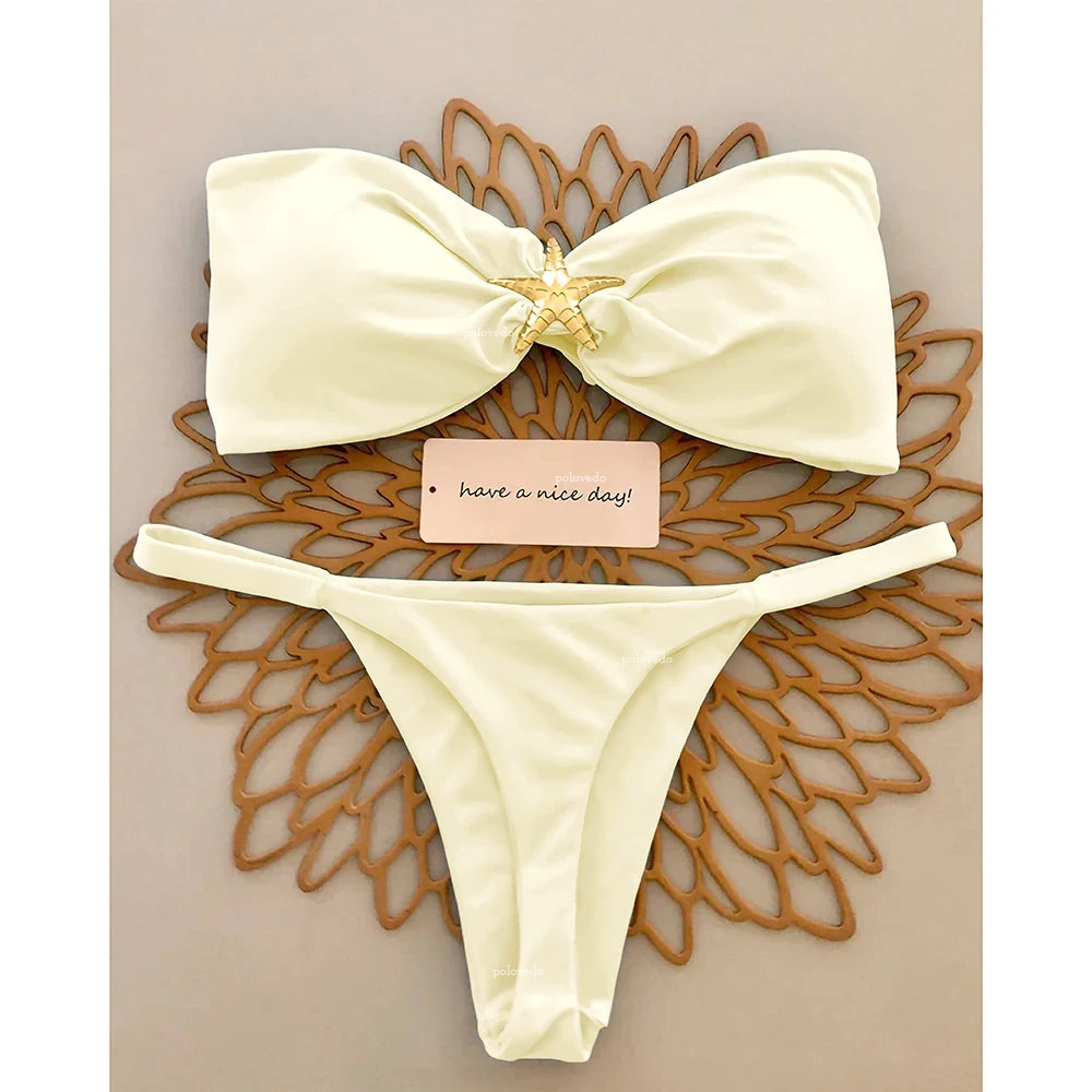 Cream knot bandeau bikini with gold starfish and micro thong bottom on a wooden sunburst tray