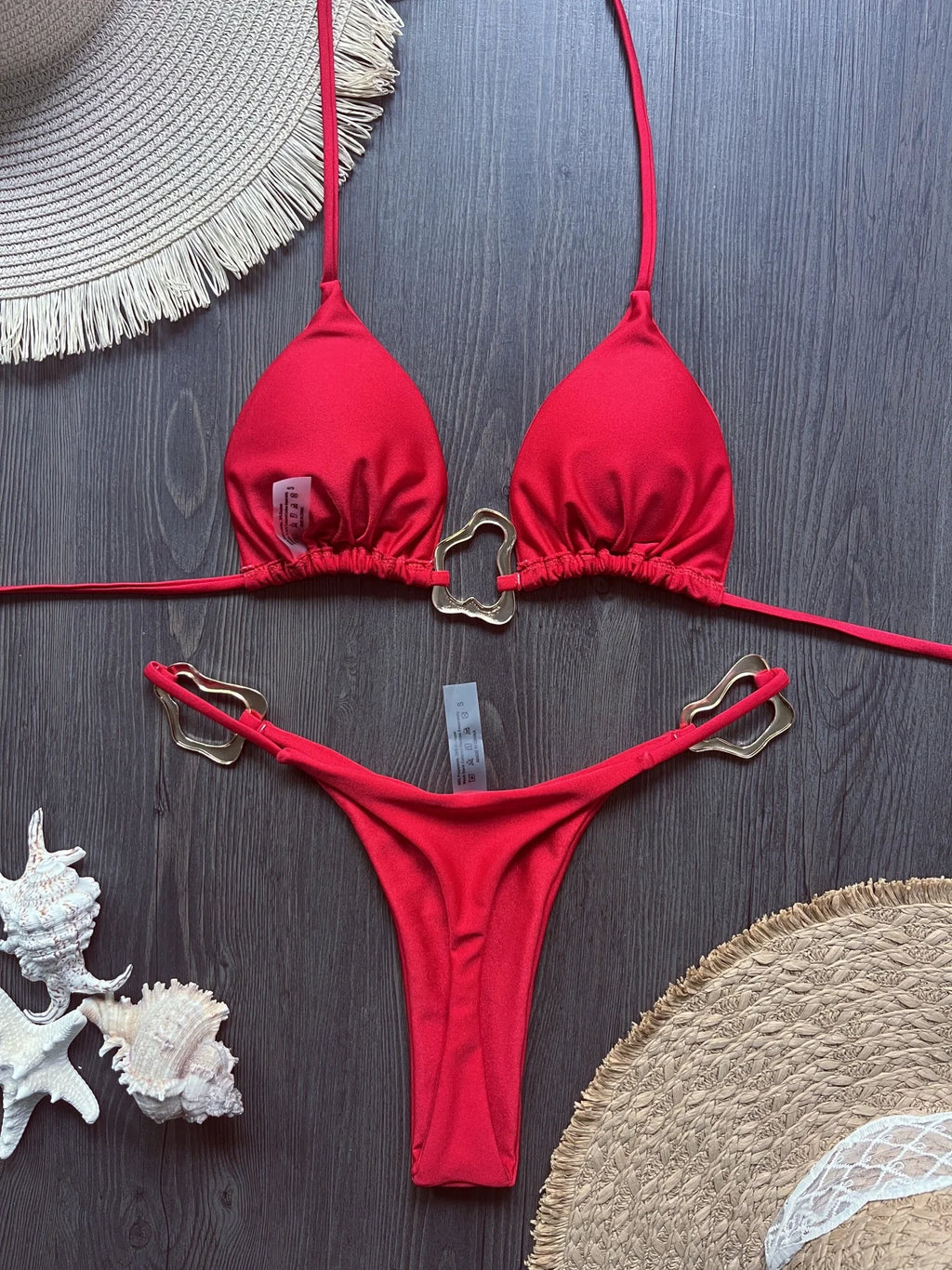 Red halter triangle top and micro thong bottom with metal rings, flat lay