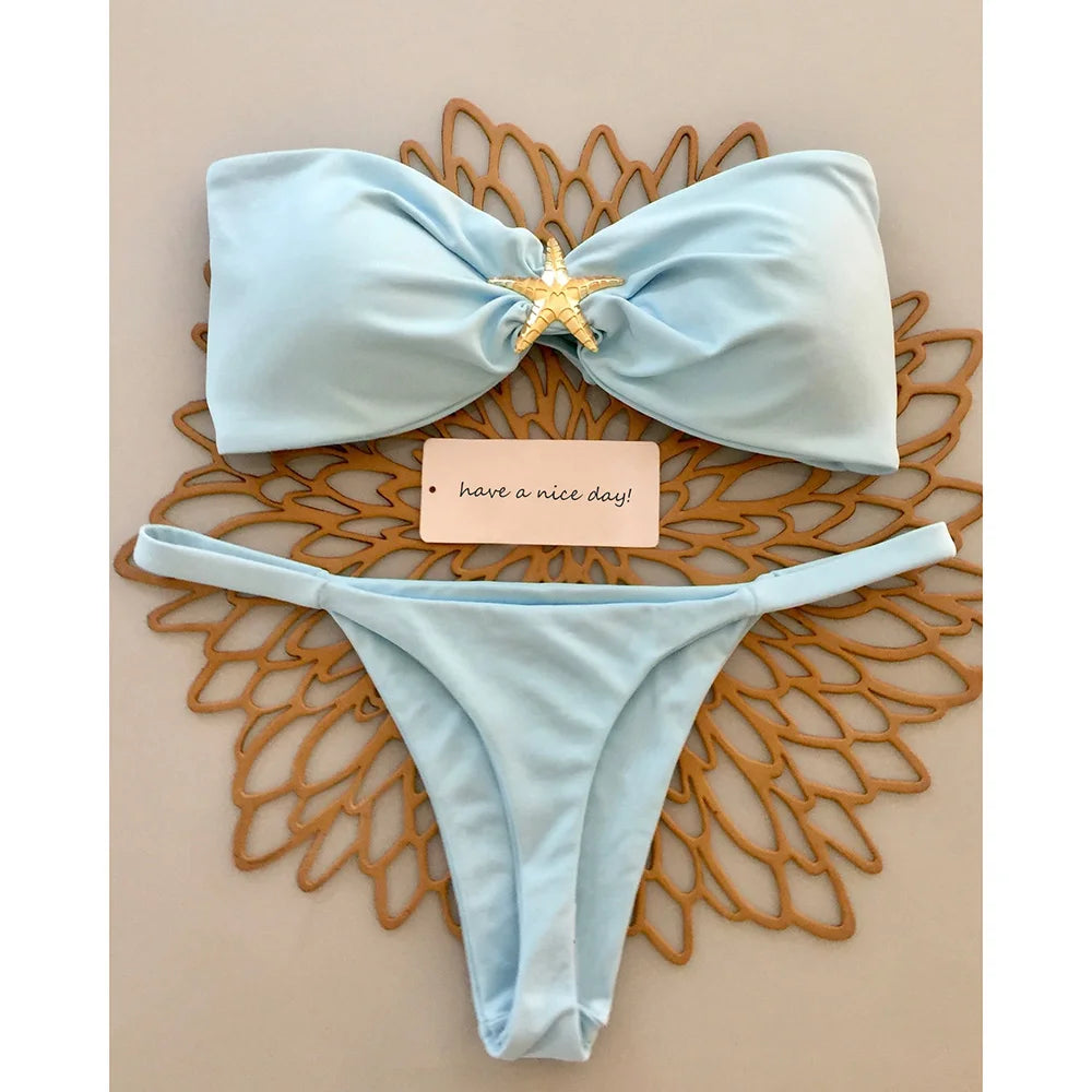 Blue knot bandeau bikini top with gold starfish and micro thong bottom on a wooden sunburst tray