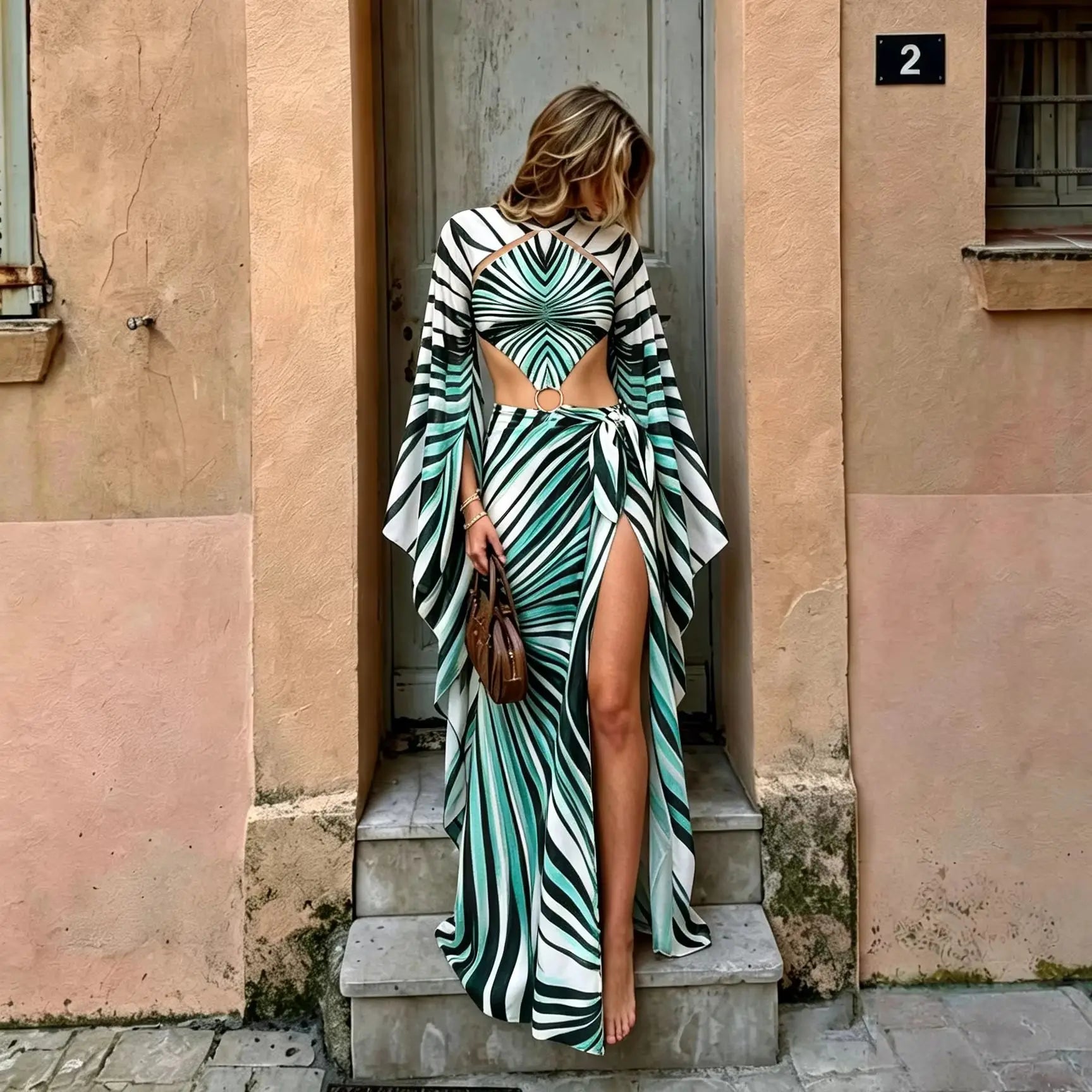Model in a green and white geometric print beach set with long cape sleeves and wrap skirt