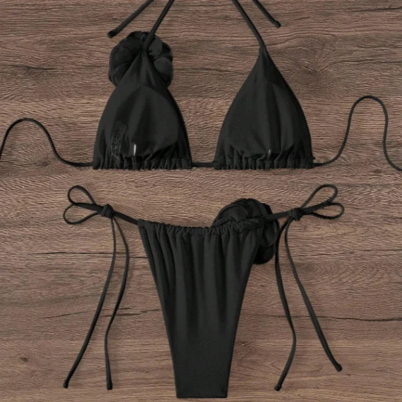 Black halter bikini top and tie side bottom with 3D rose shown from the side on wood