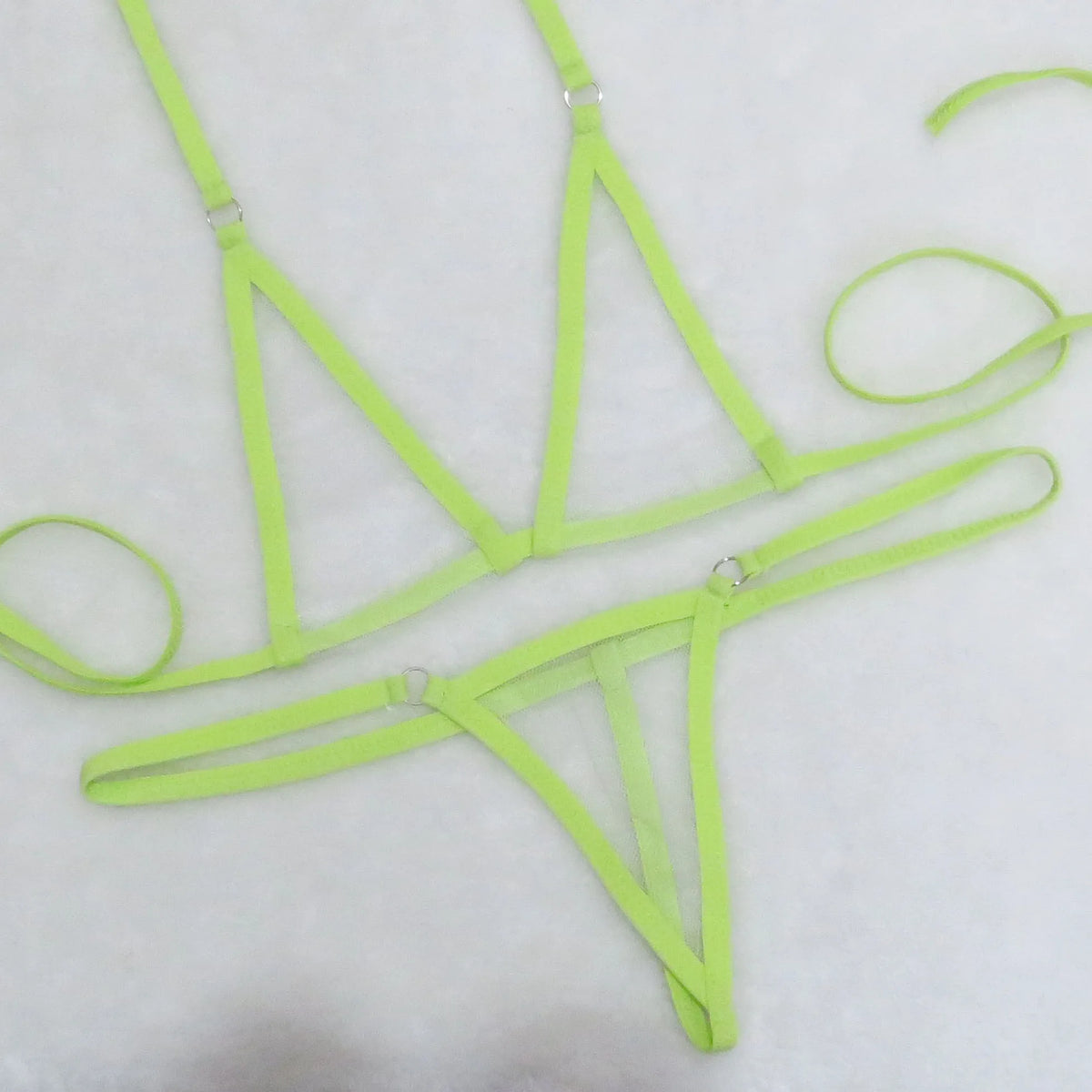 Neon green sheer mesh triangle top and string thong bottom with tie straps on white towel