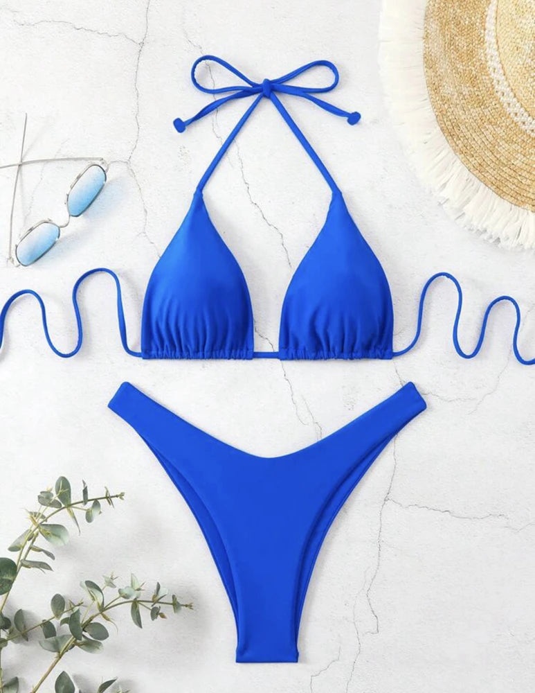 Royal blue ruffle halter bikini set with neck tie and high cut thong bottom on white marble