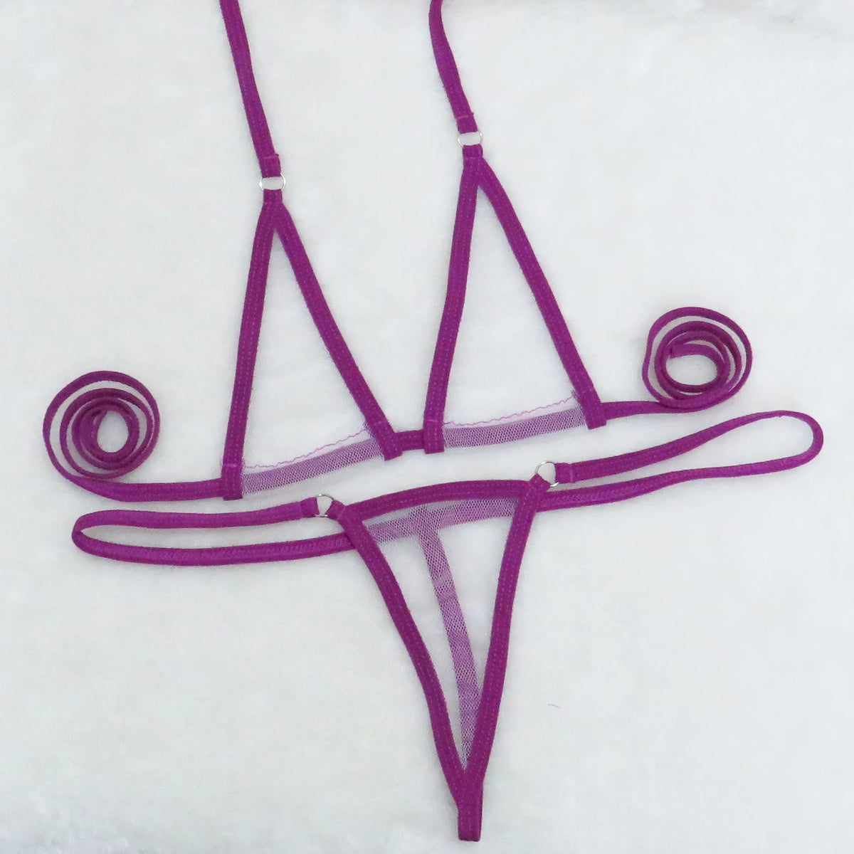 Purple sheer mesh triangle top and string thong bottom with tie straps on white towel