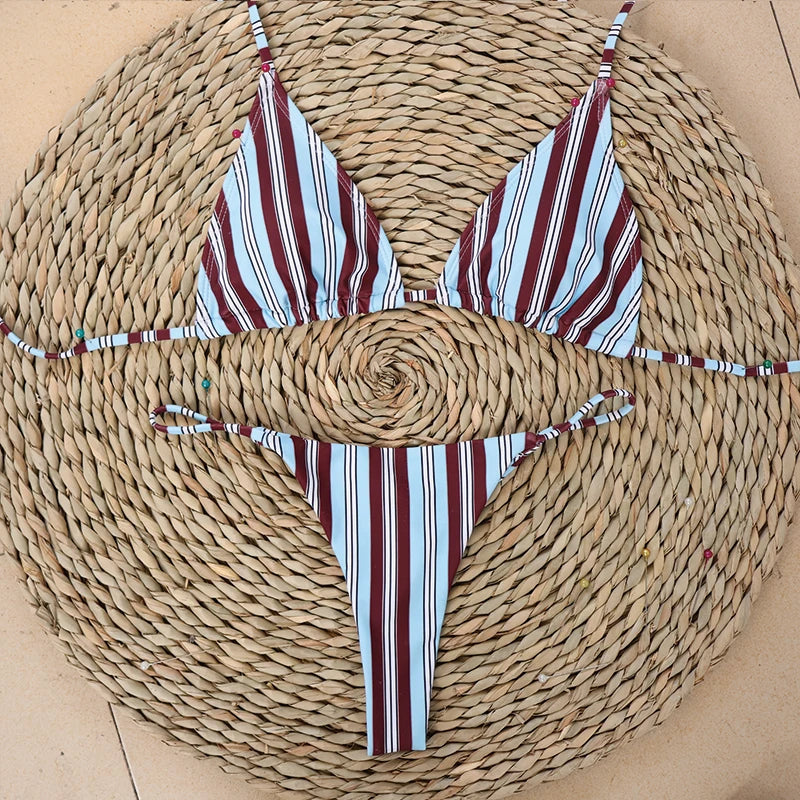Striped halter bikini top with tie-side bottoms folded flat on a woven straw mat