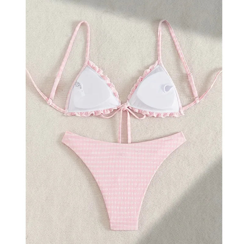 Flat lay of a light pink gingham two-piece bikini set with ruffled top and high-cut bottoms