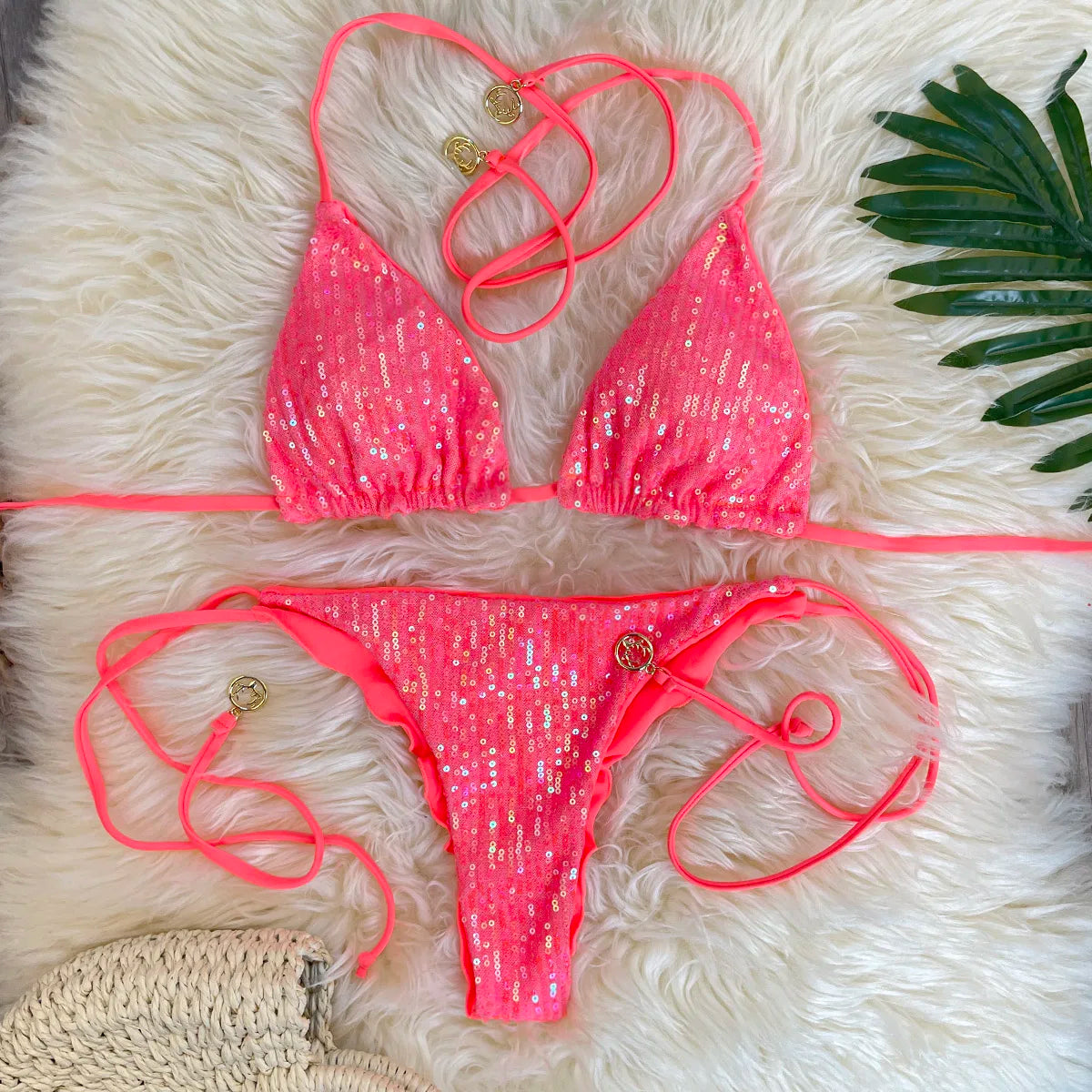 Coral sequin triangle bikini top and sequin ruffle thong bottom on white fur rug