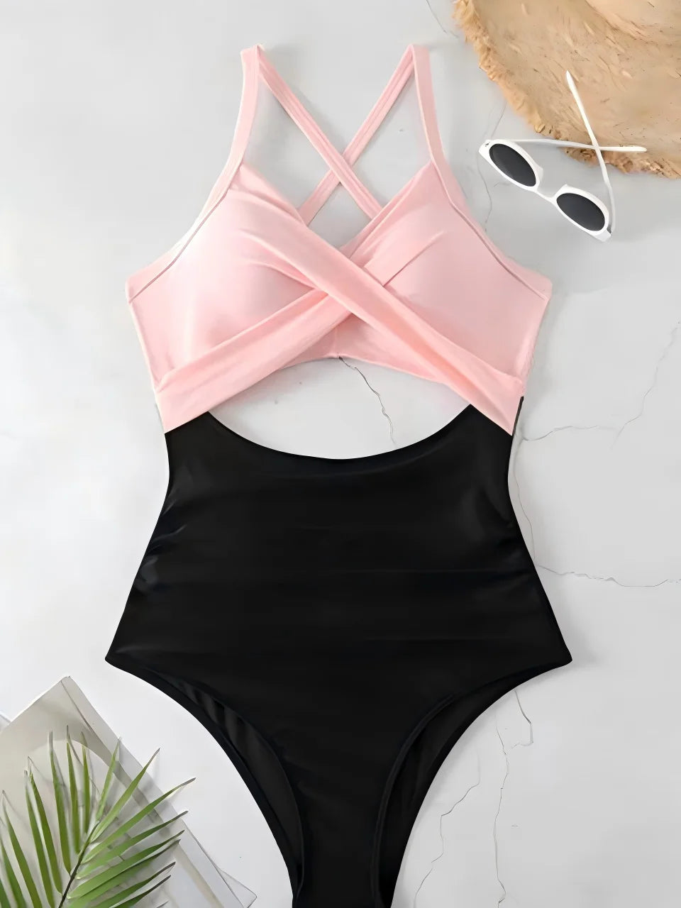 light pink cross strap top with black body ruched one piece swimsuit laid flat