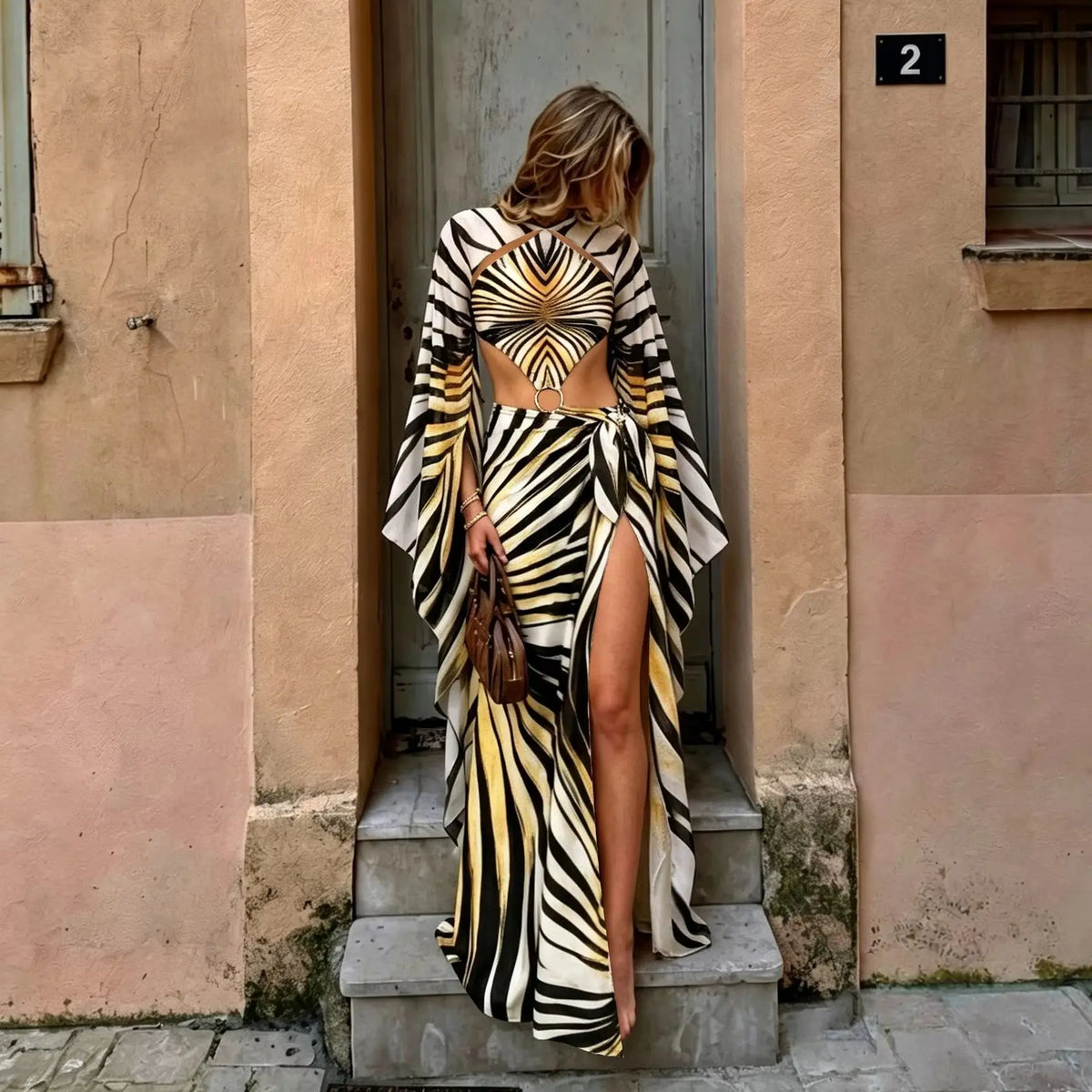 Front view of a model in a black and gold zebra print long sleeve one piece swimsuit with matching wrap skirt