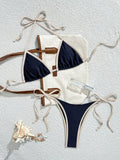 navy triangle halter bikini top with cream contrast trim and matching navy micro thong bikini bottom laid flat