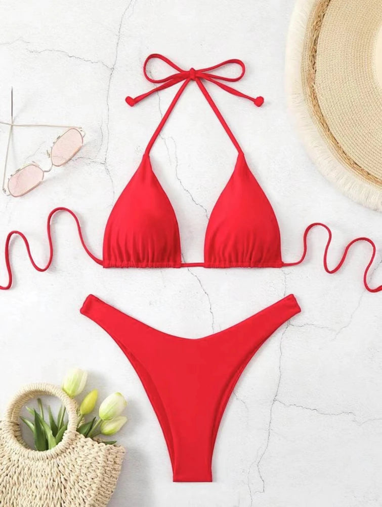 Red ruffle halter bikini set with neck tie bow and high cut thong bottom on white marble