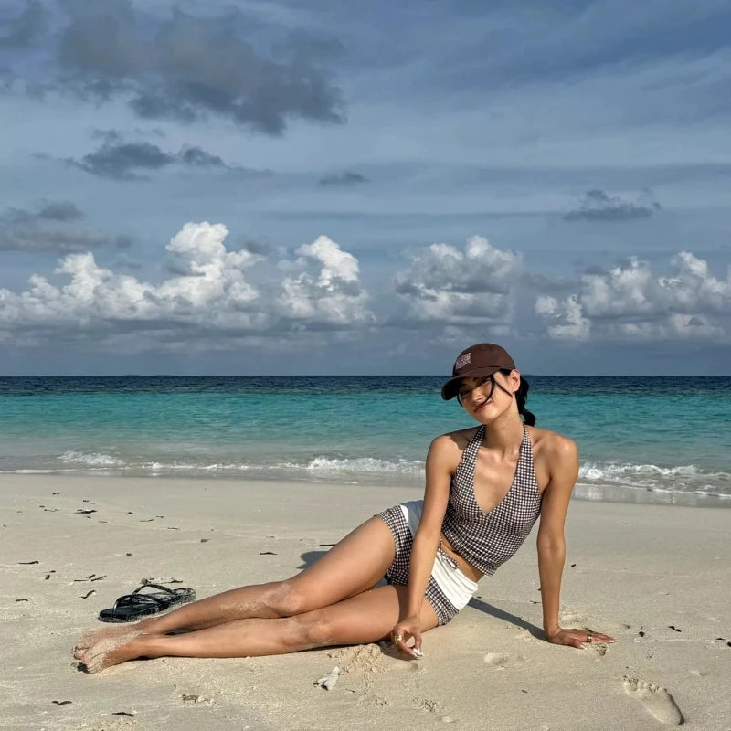 Model reclining on the beach wearing a gingham halter top and high waisted brief