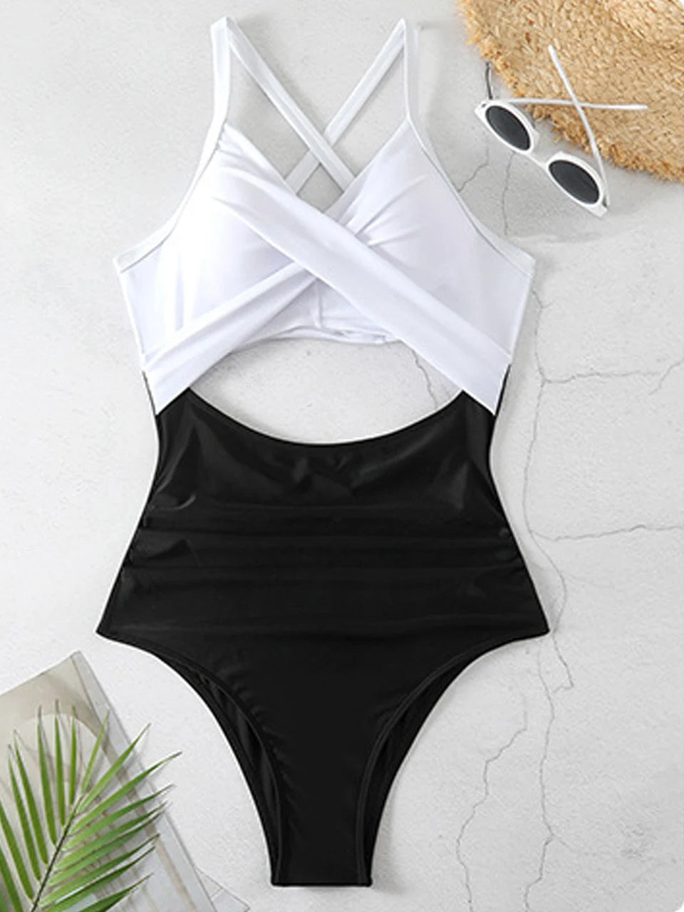 white cross strap top with black body ruched one piece swimsuit laid flat
