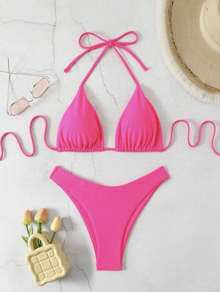 Hot pink ruffle halter bikini set with neck tie and high cut thong bottom on white marble