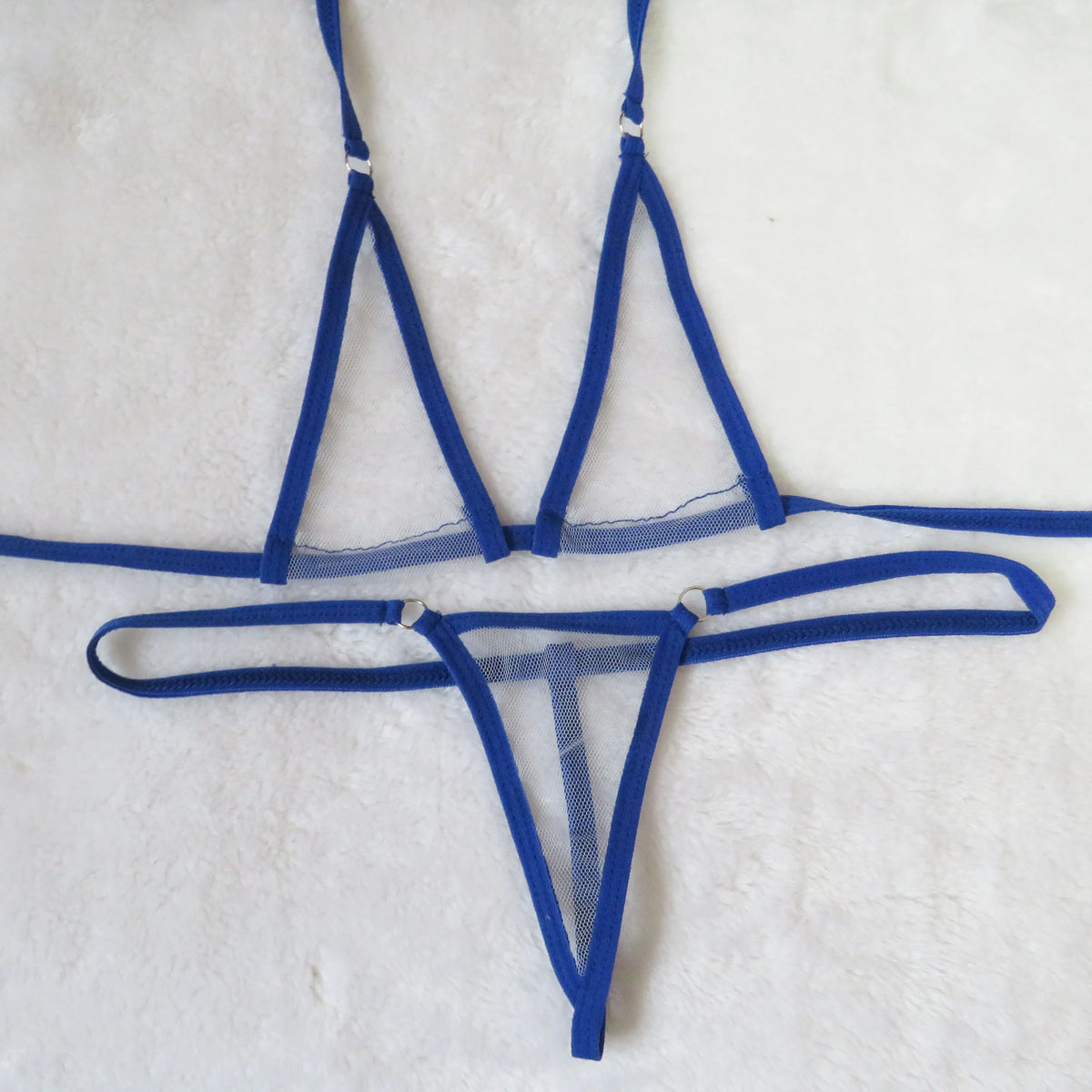 Royal blue sheer mesh micro bikini set with tie straps and silver O-ring details on white towel
