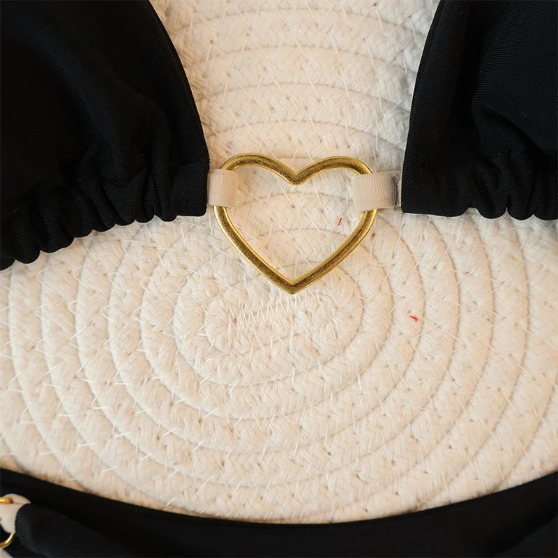 Black halter bikini top with gold heart clasp, close-up detail
