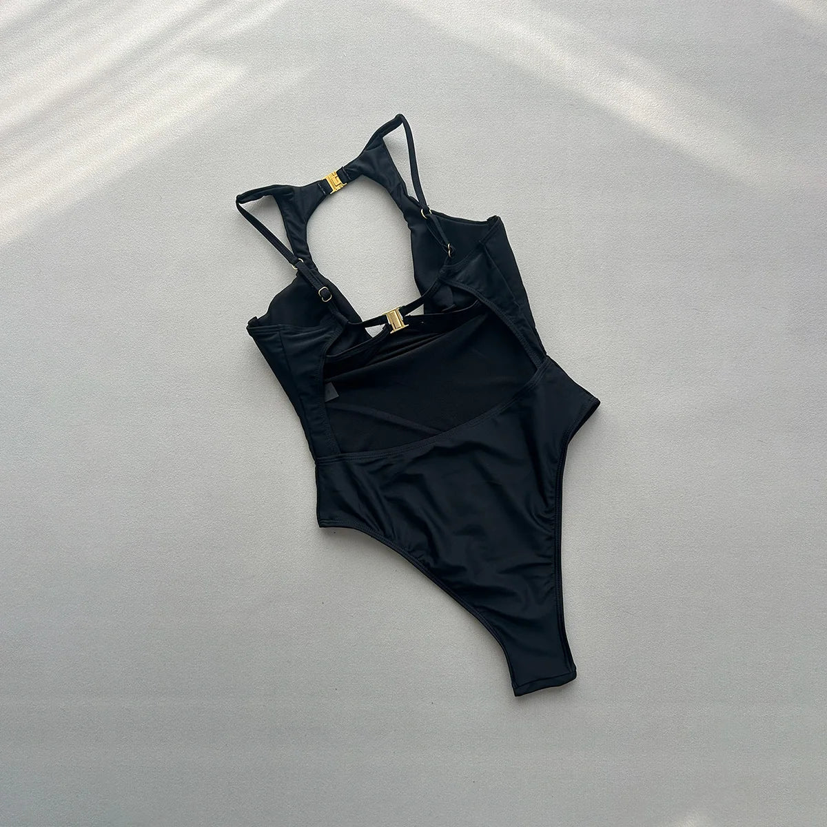 Black push up one piece swimsuit laid flat with underwire cups and center cutout