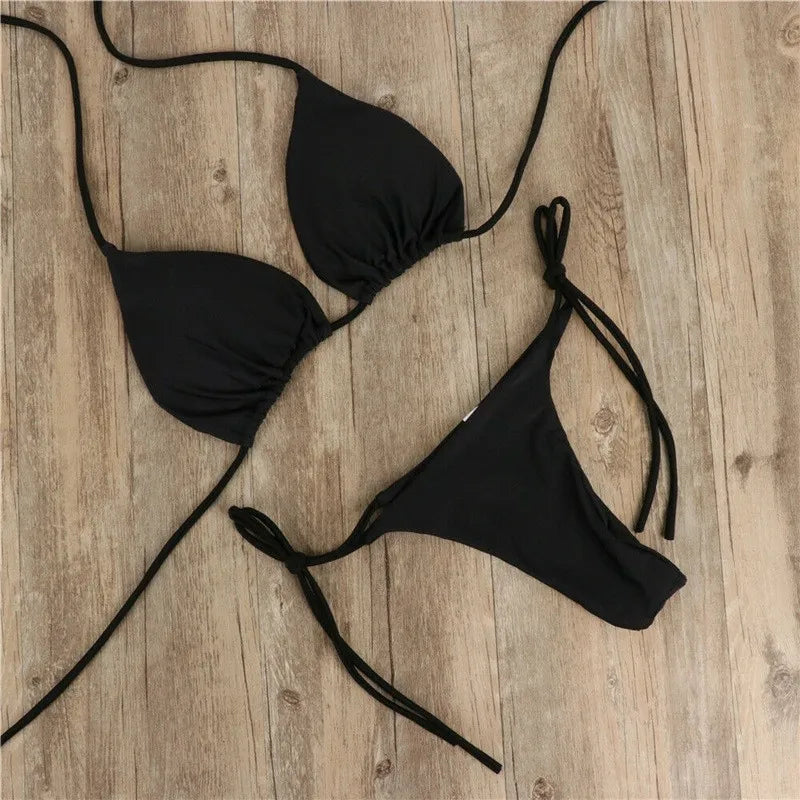 black push up triangle bikini top and thong bottom laid flat on wood