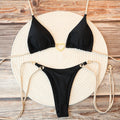 Black halter triangle bikini set with gold heart clasp, flat lay