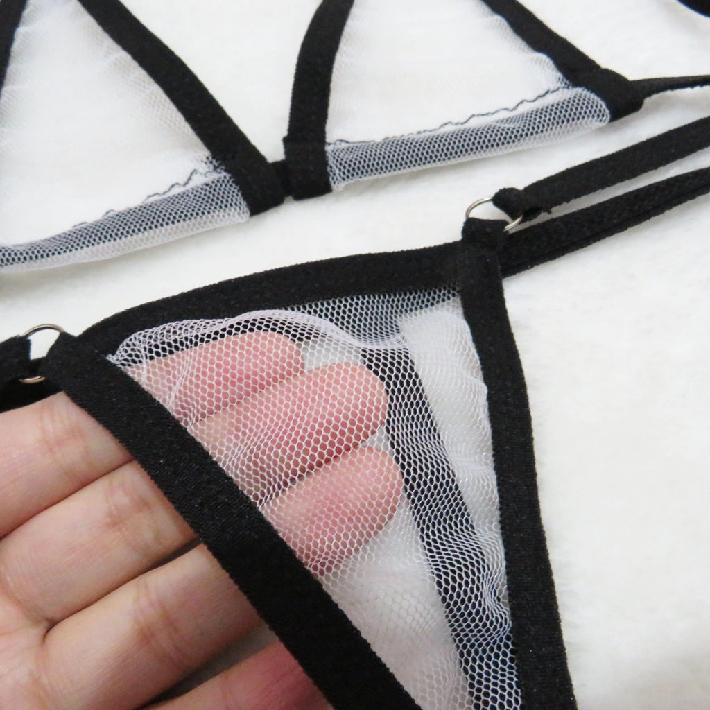 Close-up of sheer mesh panel on black string thong bottom with hand behind the fabric