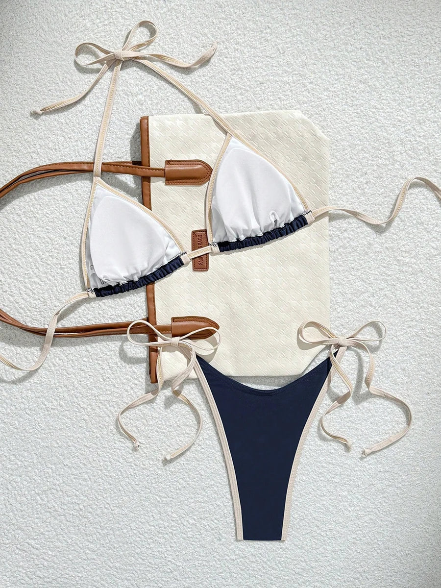 white triangle halter bikini top with navy contrast underband and matching navy micro thong bottom on a tote