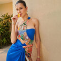 Blue one-shoulder swimsuit with halter neck, tropical print front panel, and drape