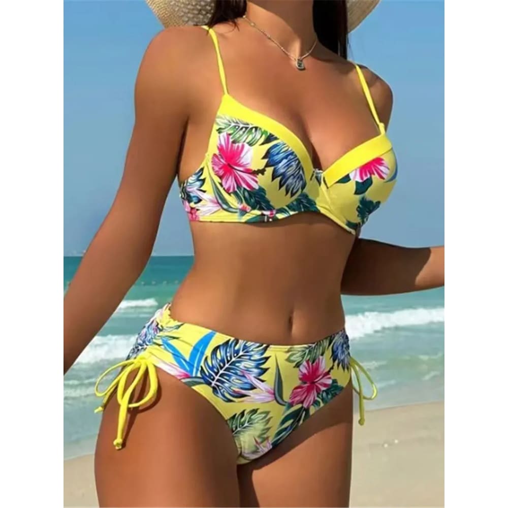 Bright yellow floral underwired mid‑waist bikini set with pink hibiscus and green leaf patterns featuring thin straps and side ties
