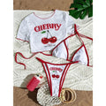 Dreiteiliges Bikini-Set flach gelegt: weißes Shirt und Bikini mit rotem Kirschenprint