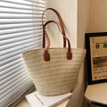 Beige straw tote with brown leather double handles and front leather tabs