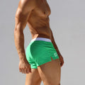 Green low-waist swim trunks with back view and white logo on side