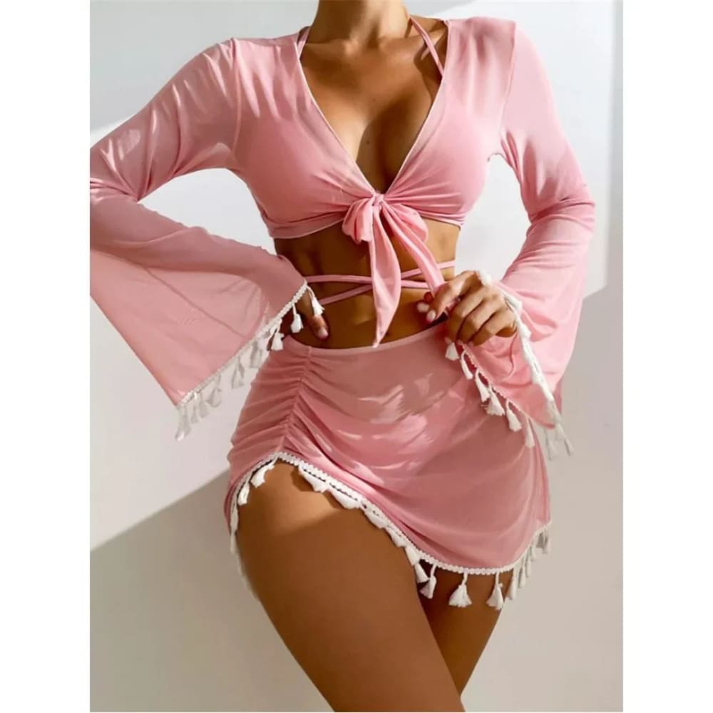 A soft pink boho tassel bikini set with a tied front top and tassel skirt featuring white tassels along edges
