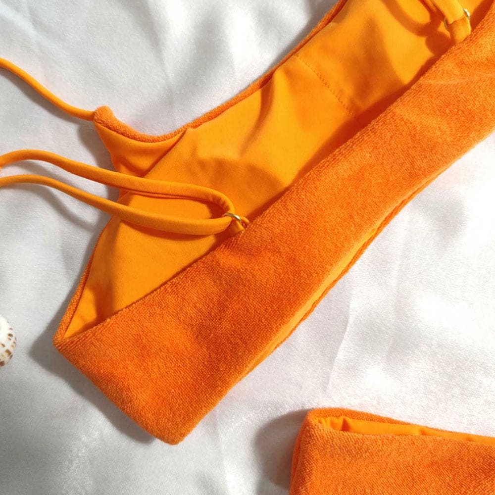 Close-up: burnt-orange terry bikini strap and high-cut leg opening, secure tie details