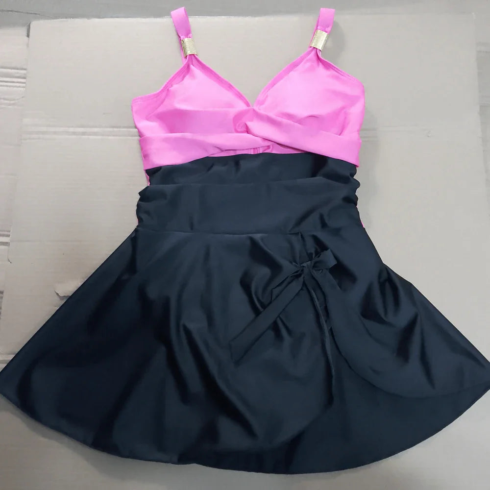A vibrant pink and black satin tummy control swimdress one-piece with adjustable straps and gold-toned hardware