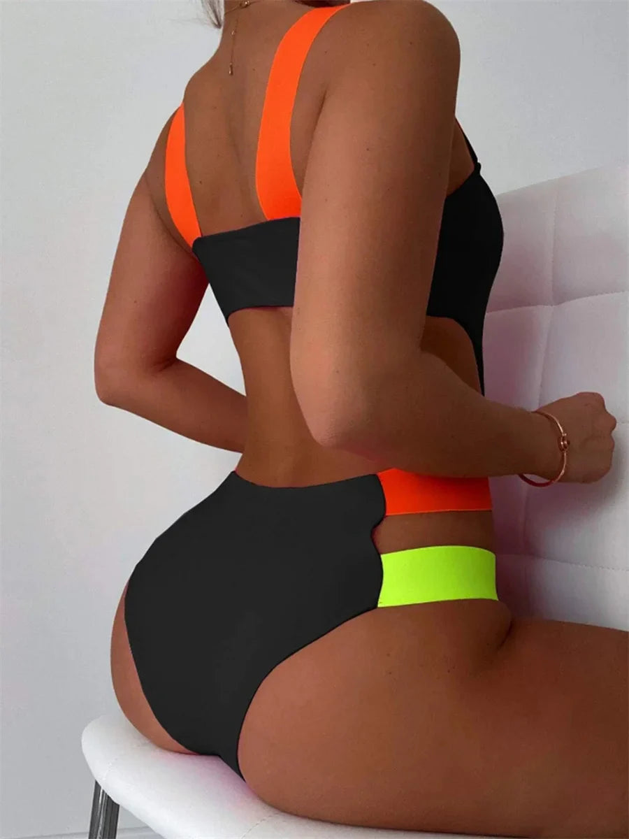 Vibrant neon-strap black one-piece swimsuit with bold black, neon orange, and lime green color blocks and hollow back
