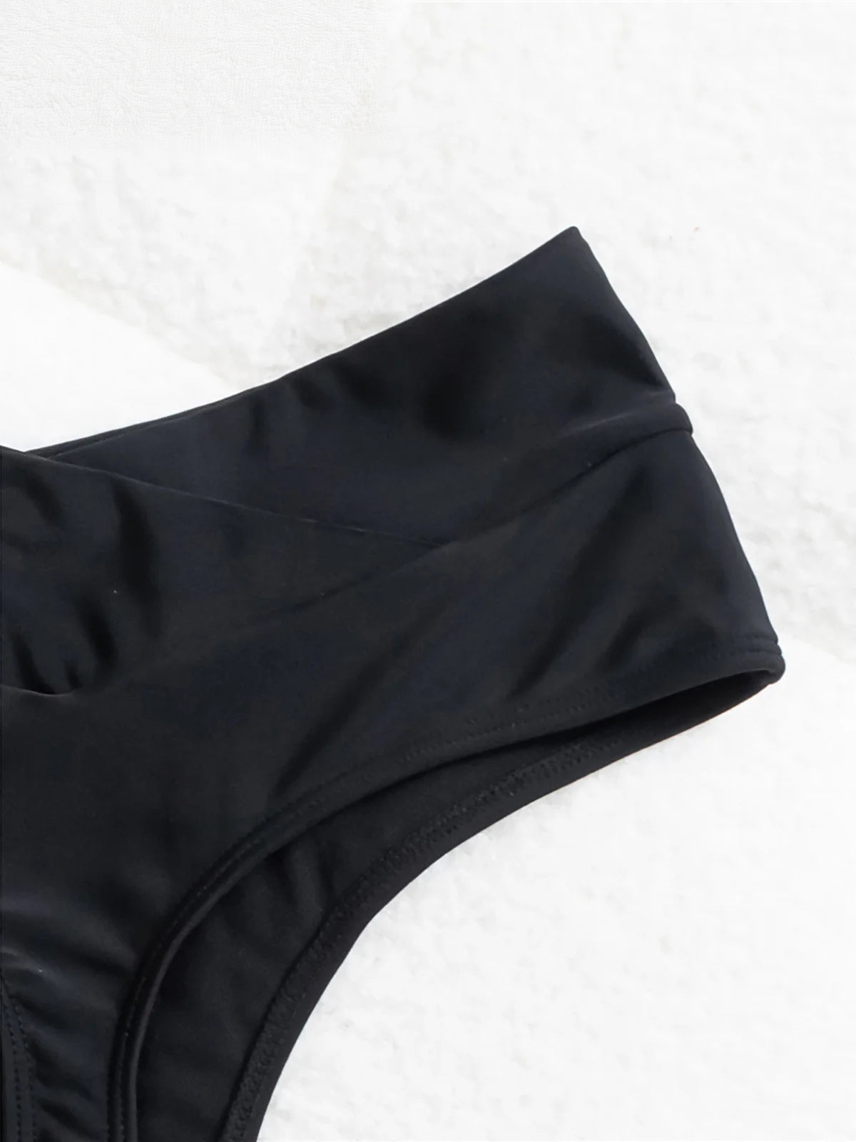 Close-up of black high waist crossed waistband fabric and flatlock seam on white towel